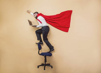 businessman wearing superhero cape and holding a laptop