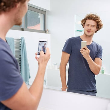man taking a selfie in front of the mirror
