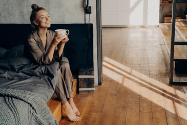 woman holding a cup of coffee while sitting on the bed