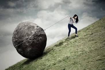 a woman pulling a rock up the hill