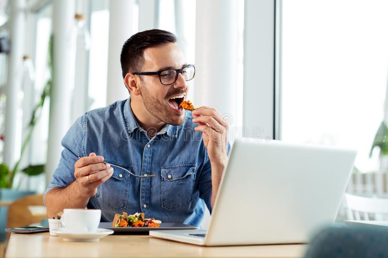 businessman eating food in front of laptop
